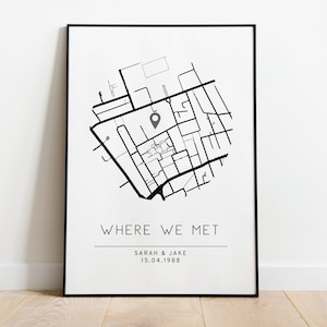 May include: A black and white print of a city map with a pin marking a location. The text below the map reads "Where We Met", "Sarah & Jake", and "15.04.1988".