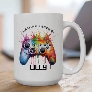 May include: White ceramic coffee mug with a colorful video game controller graphic and the text "Gaming Legend" and "Lilly".