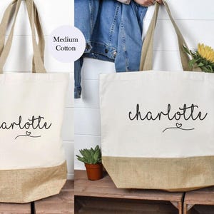May include: Two tote bags with the name "charlotte" written in cursive with a small heart symbol. The smaller bag is labeled "Medium Cotton" and the larger bag is labeled "Large Cotton".