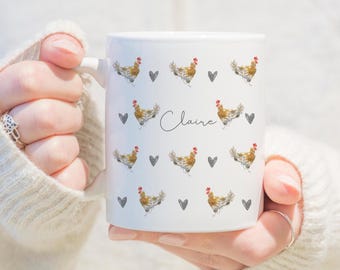 May include: White ceramic mug with a pattern of brown and white chickens and gray hearts. The name "Claire" is written in black cursive on the mug.