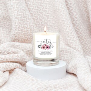 May include: A clear glass candle jar with a white label that says "sister" in a decorative font. The label also includes a floral design and the text "Lauren, I love you, you are the best sister ever. Love Jade x 200ml Hand Poured Candle".