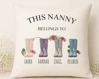 May include: A square off-white throw pillow featuring the black text THIS NANNY BELONGS TO above four pairs of illustrated rain boots in pink, purple, gray, and blue, each accented with flowers and the names Laura, Hannah, Craig, and Reuben.