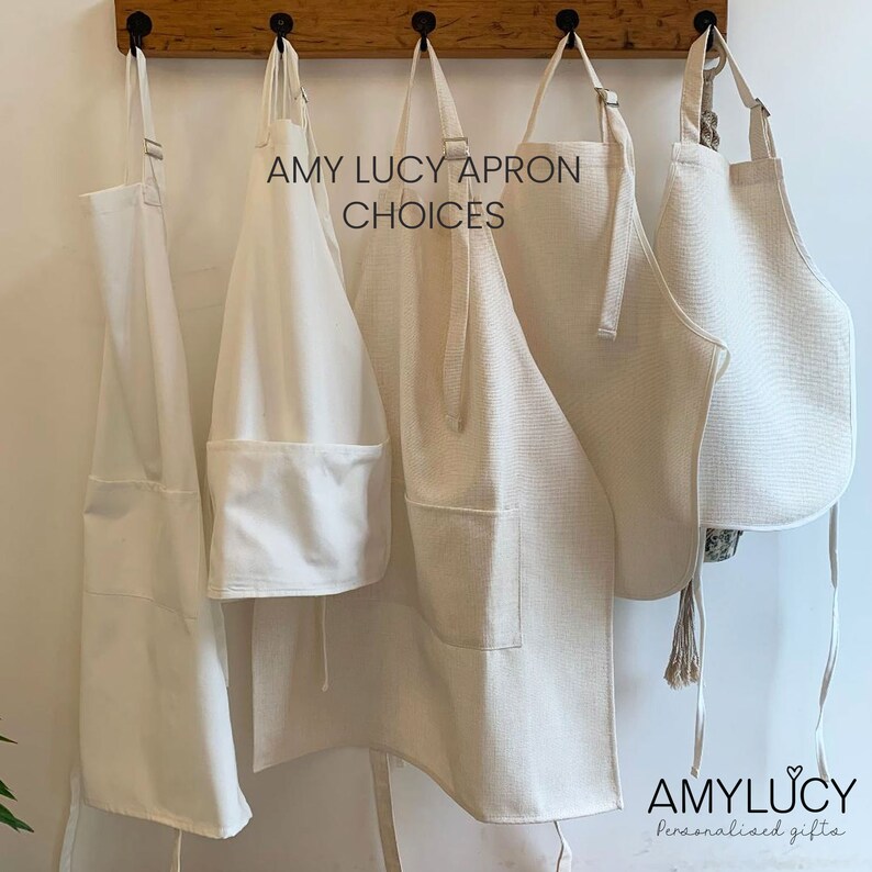 May include: Four different styles of plain white aprons hanging on hooks. The text "AMY LUCY APRON CHOICES" is above the aprons. The text "AMY LUCY Personalised gifts" is at the bottom of the image.