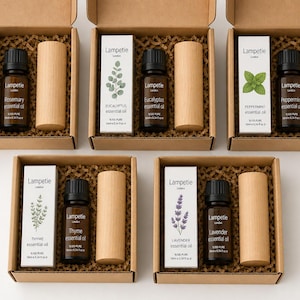 May include: A collection of essential oil gift sets in cardboard boxes. Each set includes a small brown glass bottle, a wooden cylinder, and a white box with botanical illustrations and the brand name "Lampetie London". Oils include rosemary, eucalyptus, peppermint, thyme, and lavender.