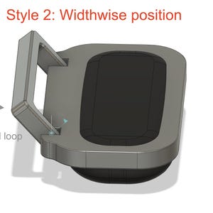 May include: A grey, rectangular, rounded-edge component featuring a swivel loop and a central black recessed area. The text "Style 2: Widthwise position" appears at the top, and the text "Swivel loop" with an arrow is visible on the left side.