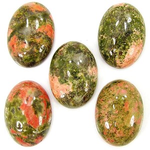 Könnte beinhalten: Fünf polierte ovale Cabochons mit einem gesprenkelten Muster aus tiefgrünen und lachsrosa Mineralien. Jeder Stein hat eine glatte, reflektierende Oberfläche mit natürlichen Farbvariationen und ist in einer Gruppe angeordnet.