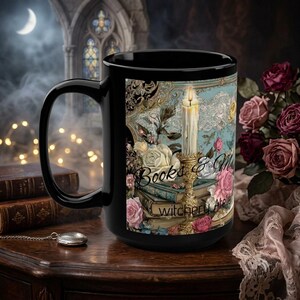 Puede incluir: Una taza de cerámica negra con un diseño impreso de una vela encendida en un candelabro dorado, libros antiguos apilados y rosas rosas y blancas. El texto "Books & Magic" y "witchery Atelier" está impreso en el centro del diseño.