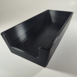 May include: A rectangular black tray with a smooth finish and a low-profile design. The tray features a U-shaped cutout on one of the shorter sides, creating an open front section. The interior base has a subtle cross-hatch texture pattern.