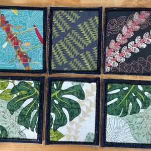 May include: Six rectangular fabric patches with dark denim borders. The top left shows a red outrigger canoe on blue water. The top middle has green triangles on dark blue. The top right features pink and white floral patterns on black. The bottom three patches display green monstera leaves on white and light green backgrounds.