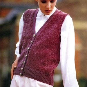 May include: A woman wearing a white shirt and a burgundy knitted waistcoat with buttons. The waistcoat has a V-neck and a textured knit.
