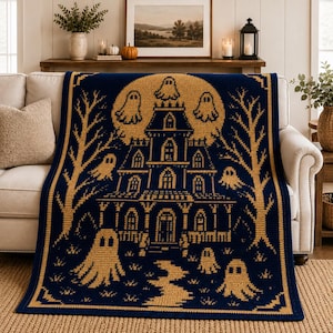 May include: A rectangular crochet blanket featuring a dark navy blue background with a contrasting golden yellow pattern. The design depicts a multi-story haunted house centered in front of a large full moon, surrounded by bare trees and several ghosts.