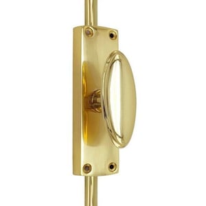 May include: A polished brass window sash lock featuring an oval-shaped handle mounted on a rectangular base plate. The hardware includes two visible screw holes at the top and bottom of the plate, with a vertical rod extending from both ends.