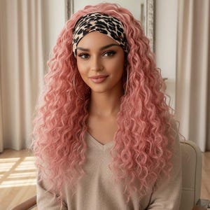 Puede incluir: Una peluca larga y rizada de color rosa pastel, peinada con raya al medio y una diadema ancha con estampado de leopardo marrón y negro. El cabello cae en rizos voluminosos y definidos que llegan más allá de los hombros, enmarcando el rostro.