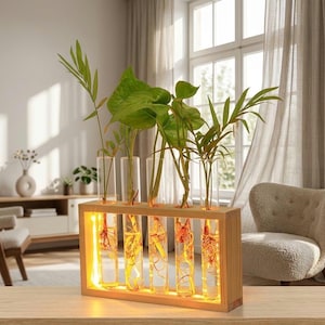 May include: A wooden propagation station with six clear glass tubes, each holding a plant cutting. The wooden frame has a warm, yellow glow from the internal lighting. The plants have green leaves and visible roots.