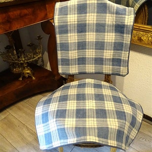 May include: A blue and white plaid chair cushion with a dark blue border. The cushion is placed on a wooden chair with a curved back.