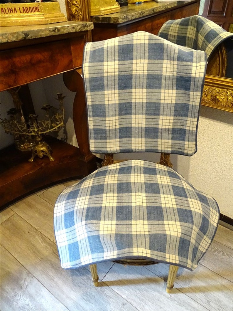 May include: A blue and white plaid chair cushion with a dark blue border. The cushion is placed on a wooden chair with a curved back.