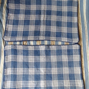May include: Two blue and white plaid pillowcases with a dark blue border.