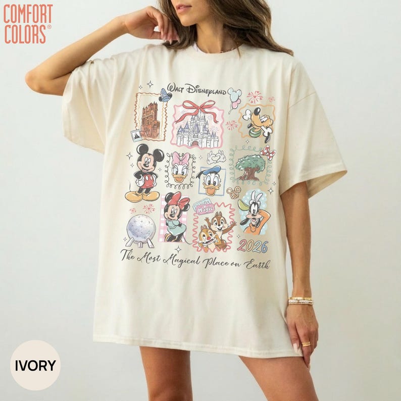 May include: An ivory t-shirt featuring a graphic print with the text Walt Disneyland and The Most Magical Place on Earth 2026. The design includes illustrations of Mickey Mouse, Minnie Mouse, Donald Duck, Daisy Duck, Goofy, Chip and Dale.