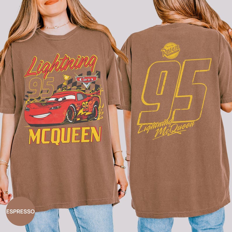 May include: Espresso-colored t-shirt featuring a graphic of Lightning McQueen from the Cars movie. The front design includes the text "Lightning 95 McQueen" with a red race car. The back displays a large yellow "95" and "Lightning McQueen" text.