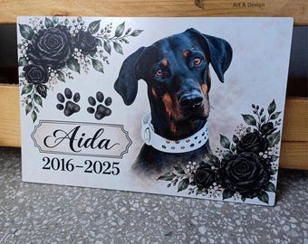May include: A rectangular memorial plaque featuring a portrait of a black and tan Doberman wearing a white studded collar. The design includes black roses, two paw prints, the name Aida in script, and the years 2016-2025 in black text.
