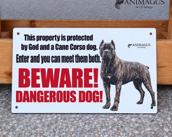 May include: A rectangular white metal sign featuring a brindle Cane Corso dog and black text that reads: This property is protected by God and a Cane Corso dog. Enter and you can meet them both. The sign also includes the red text BEWARE! DANGEROUS DOG!