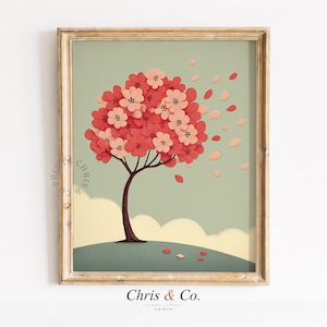 Pode incluir: Uma impressão de arte emoldurada com uma árvore estilizada com flores vermelhas e rosa. A árvore está em uma colina verde contra um fundo verde claro. A obra de arte inclui pétalas caindo e o texto "Chris & Co."