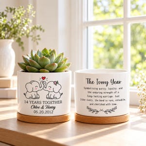 May include: Two white ceramic cylindrical planters with bamboo saucers. One planter holds a green succulent and features two cartoon elephants, the text 14 YEARS TOGETHER, Chloe & Henry, and 05.20.2012. The other displays The Ivory Year text.