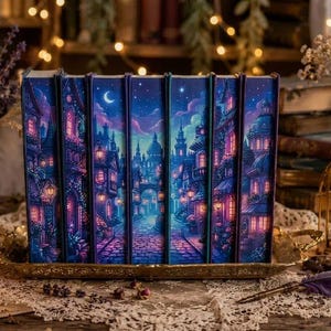 Può includere: Un set di sei libri disposti fianco a fianco, caratterizzati da un'illustrazione continua di una strada cittadina notturna con ciottoli, finestre illuminate e una luna crescente in un cielo blu profondo e viola, creando una scena panoramica.