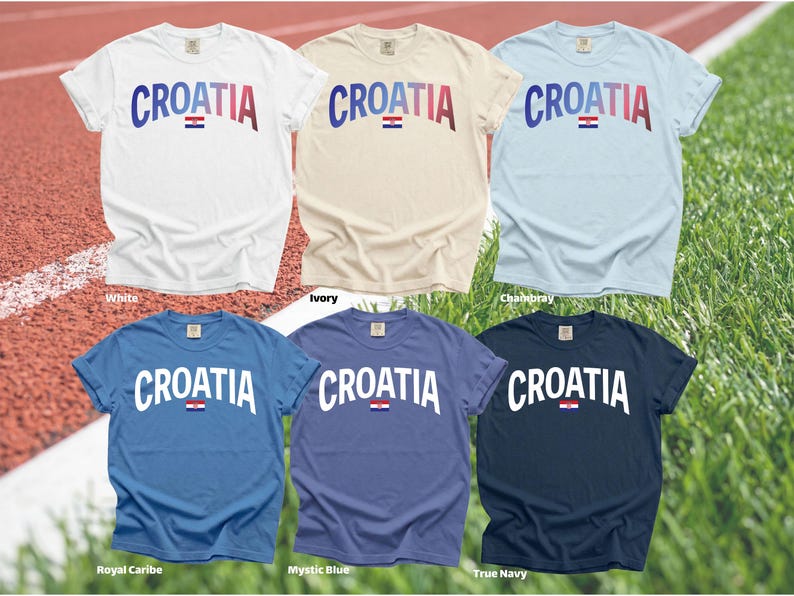 May include: Six short-sleeved t-shirts in various colors, including white, ivory, and blue. Each shirt displays the word "CROATIA" in a curved font, with the Croatian flag beneath the text. The shirts are on a red track and green grass background.