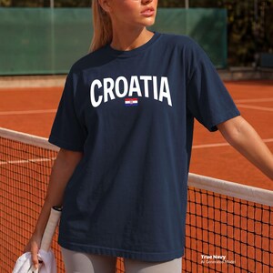 May include: Navy blue t-shirt with the word "CROATIA" in white block letters and a small Croatian flag graphic. The shirt is a crew neck style.