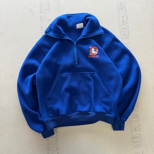 Op de afbeelding: Een koningsblauwe fleece trui met een kwart ritssluiting en een kangoeroezak. Het Denver Broncos logo is in oranje en wit op de borst geborduurd. De trui heeft een hoge kraag en geribde manchetten en zoom.