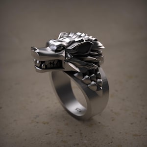May include: A silver ring featuring a detailed wolf head design. The wolf's head is sculpted with sharp teeth and textured fur, set on a wide band. The ring is made of a shiny, metallic material.