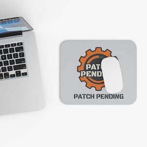 May include: A computer mouse and mousepad with the text "PAT PEND" inside an orange gear design. The words "PATCH PENDING" are below the gear. A laptop is in the background.