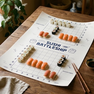 May include: A sushi battleship game set on a white paper grid, with various sushi rolls arranged as game pieces. The game board is on a wooden table, with chopsticks and a small bowl of soy sauce nearby. The text "SUSHI BATTLESHIP" is printed on the board.