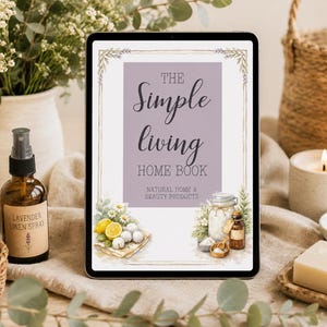 May include: A digital tablet displays "The Simple Living Home Book" with illustrations of natural home and beauty products. A brown glass bottle of lavender linen spray, a candle, and a bar of soap are also visible.