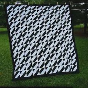 May include: A black and white quilt featuring a repeating geometric pattern of slanted rectangles, titled Illusion. The quilt is displayed hanging from a line. Text at the bottom reads: A quilt pattern by: Jennifer Overstreet www.ghquilting.com.
