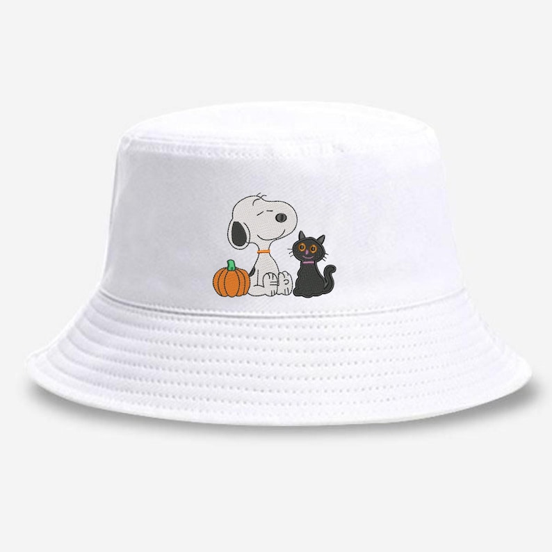 May include: A white bucket hat featuring a central graphic of a white cartoon dog with a black ear, a small orange pumpkin, and a black cat with large yellow eyes. The hat has a flat top, a downward-sloping brim, and a clean, solid white fabric finish.