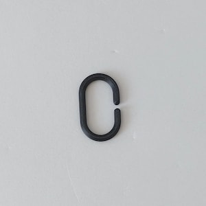 May include: A matte black oval-shaped link with a small opening on one side. The link features a textured surface with visible horizontal lines consistent with 3D printed construction, forming a continuous loop with a single break in the frame.