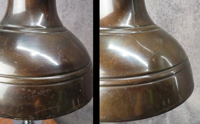 Puede incluir: Primer plano de una base de l&aacute;mpara de color bronce. La base tiene una forma redondeada, como de campana, con una superficie ligeramente texturizada. El metal refleja la luz, creando reflejos y sombras. La base de la l&aacute;mpara parece ser vintage o antigua.