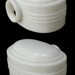 Puede incluir: Dos l&aacute;mparas blancas de forma ovalada, con una parte superior redondeada y tres ranuras horizontales. Una l&aacute;mpara tiene un peque&ntilde;o asa circular. Las l&aacute;mparas est&aacute;n sobre un fondo negro.