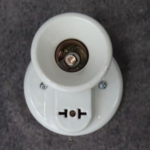 Puede incluir: Un aplique de luz de porcelana blanca con base circular y pantalla c&oacute;nica. El aplique tiene una toma de corriente de dos clavijas y est&aacute; montado con dos tornillos. El centro del aplique revela un casquillo de color lat&oacute;n.