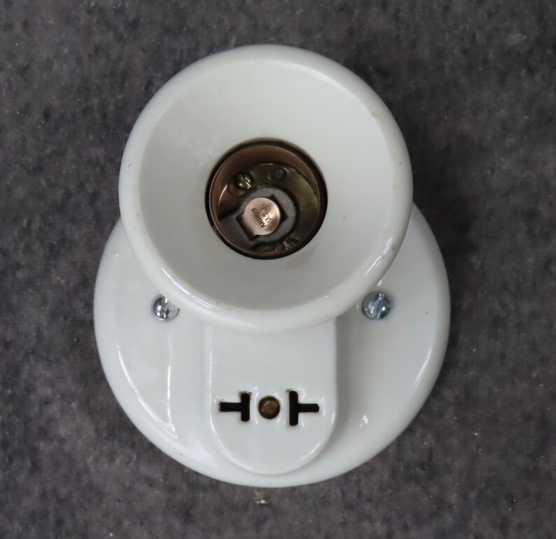 Puede incluir: Un aplique de luz de porcelana blanca con base circular y pantalla c&oacute;nica. El aplique tiene una toma de corriente de dos clavijas y est&aacute; montado con dos tornillos. El centro del aplique revela un casquillo de color lat&oacute;n.