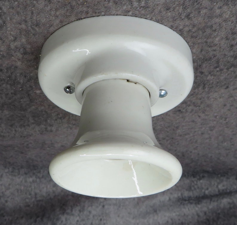 Puede incluir: Una l&aacute;mpara de techo de cer&aacute;mica blanca con una base redondeada y un casquillo acampanado. La l&aacute;mpara se fija al techo con dos tornillos. La l&aacute;mpara es de dise&ntilde;o cl&aacute;sico.