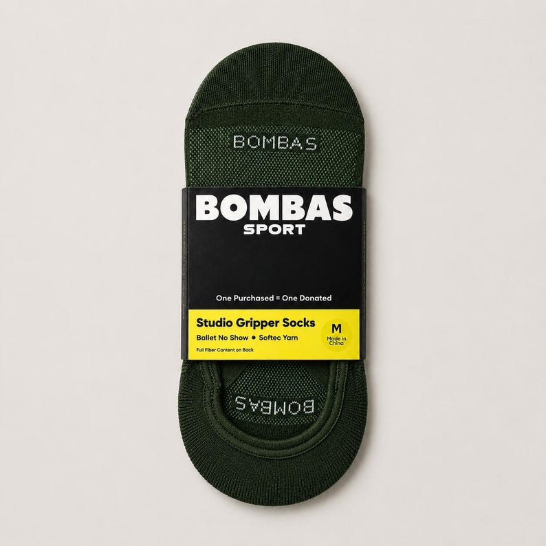 Pode incluir: Meias Studio Gripper Bombas verde escuro, tamanho M, com o nome da marca e "SPORT" impressos na embalagem. A embalagem tamb&eacute;m diz "One Purchased = One Donated". As meias s&atilde;o projetadas para bal&eacute; e s&atilde;o feitas com fio Softec.