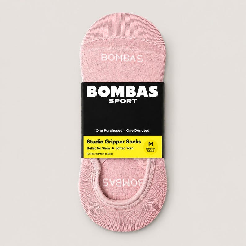 Pode incluir: Um par de meias rosa Bombas Studio Gripper. As meias s&atilde;o estilo ballet sem mostrar e apresentam o logotipo Bombas Sport em uma etiqueta preta. A etiqueta tamb&eacute;m diz "One Purchased = One Donated".