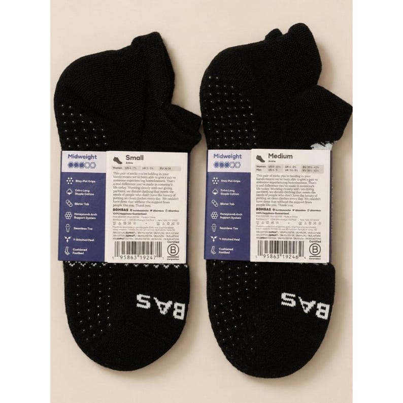 May include: Two black midweight socks with white dotted grips on the heel and sole. Each sock has a label with product details. The brand name "BAS" is printed in white on the bottom of each sock.