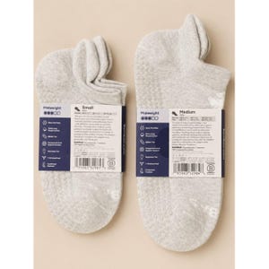 May include: Two pairs of light gray midweight socks with grip dots on the soles. Each sock has a label with product information. One label reads "Small" and the other reads "Medium".