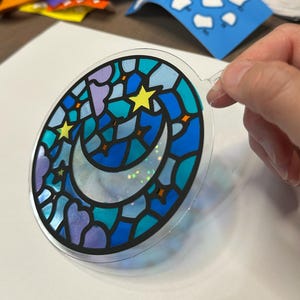 Moon and stars suncatcher kit held in a hand for scale