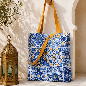 Peut inclure: Un sac fourre-tout rectangulaire orné d'un motif inspiré des carreaux aux tons bleu, blanc et jaune. Le sac est doté de deux longues anses solides jaune moutarde et d'une sangle assortie drapée sur la face avant du sac.