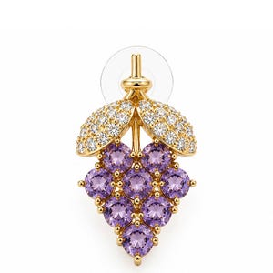 K&ouml;nnte beinhalten: Goldfarbener Ohrring in Form einer Weintraube. Die Trauben werden durch runde, violette Edelsteine dargestellt. Die Bl&auml;tter sind mit kleinen, klaren Edelsteinen besetzt. Der Ohrringstift ist sichtbar.